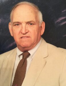 A man in a suit and tie standing next to a wall.