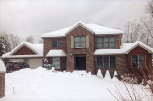 A brick house with snow on the roof and windows.