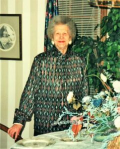 A woman standing in front of a table with flowers.