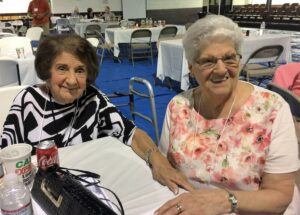 Two women sitting at a table with papers and pens.