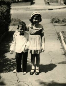 A young boy and girl standing on the sidewalk.