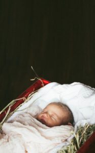 A baby is sleeping in the corner of a bed.