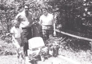 A family posing for the camera in front of their motorcycle.