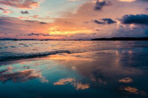 A sunset over the ocean with clouds in the sky.