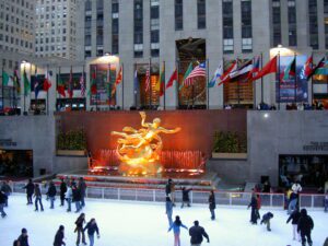 A group of people skating on ice near the building.