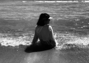 A woman sitting on the beach in water.