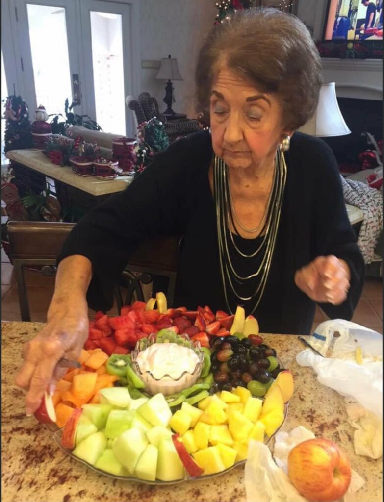 A woman is cutting up fruit on the table.